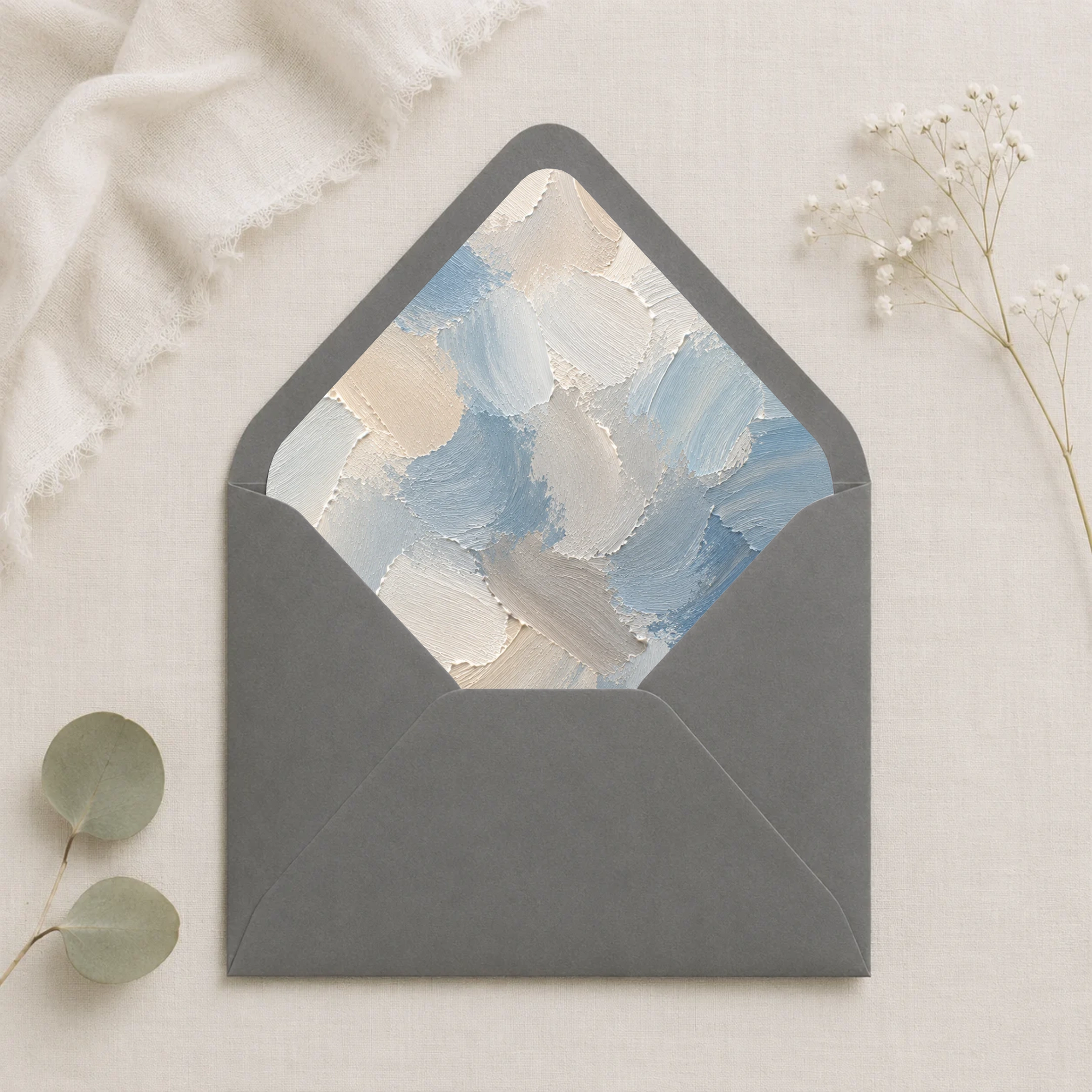 Dusty Canvas Envelope Liner Template displayed inside a dark grey envelope, featuring painterly dusty blue, ivory, cream, and soft grey abstract brushstrokes for elegant wedding invitations.
