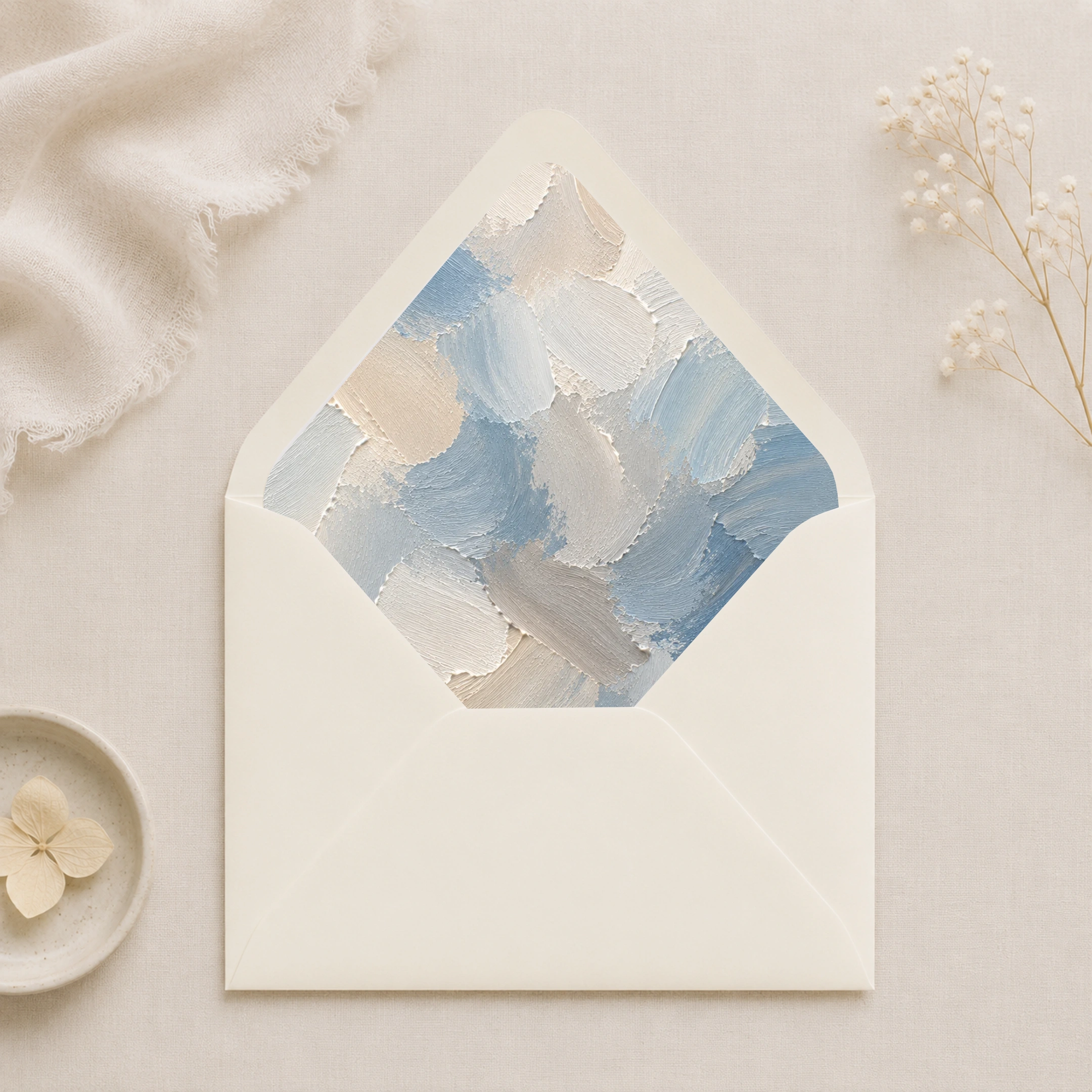 Dusty Canvas Envelope Liner Template displayed inside an ivory envelope, featuring painterly dusty blue, ivory, cream, and soft grey abstract brushstrokes for elegant wedding invitations.